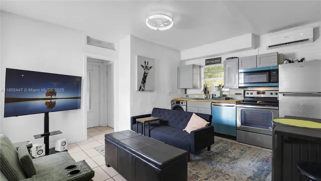a living room with stainless steel appliances furniture a rug and a view of kitchen