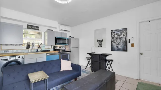 a large living room with stainless steel appliances granite countertop a couch a computer on desk and chair with wooden floor