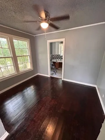 an empty room with wooden floor fan and windows