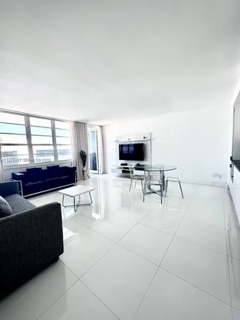 a living room with furniture a flat screen tv and a window