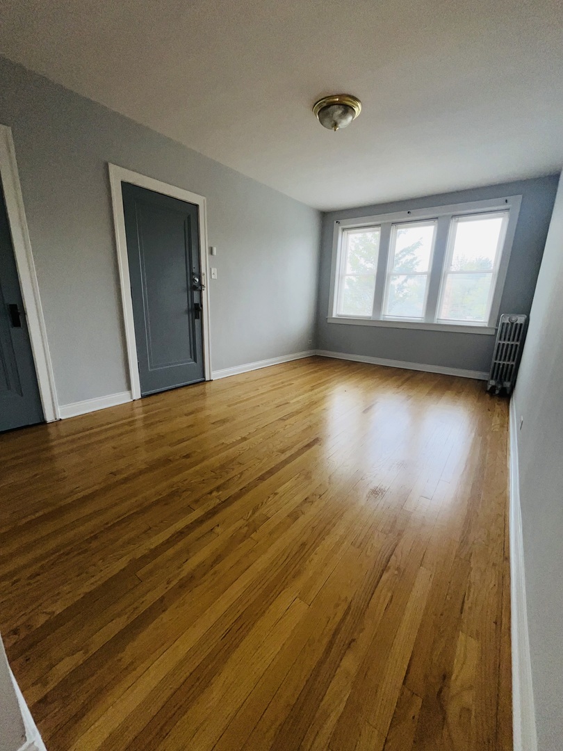 5852 West Higgins Avenue, Unit 3B Chicago, IL 60630 - Photo 2 of 9 a view of an empty room with wooden floor and a window
