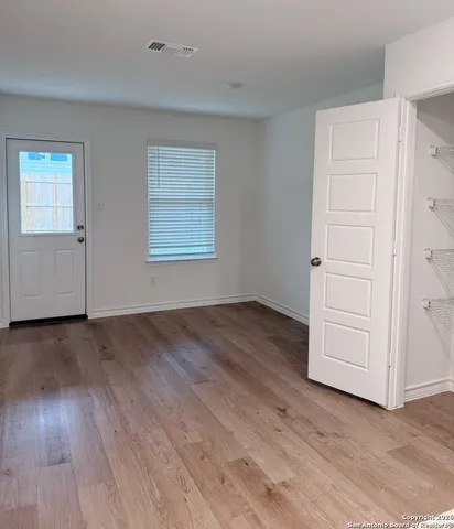 an empty room with wooden floor closet and windows