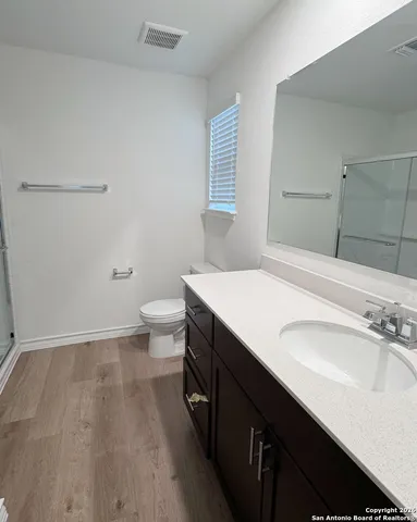 a bathroom with a sink a toilet a shower and a window