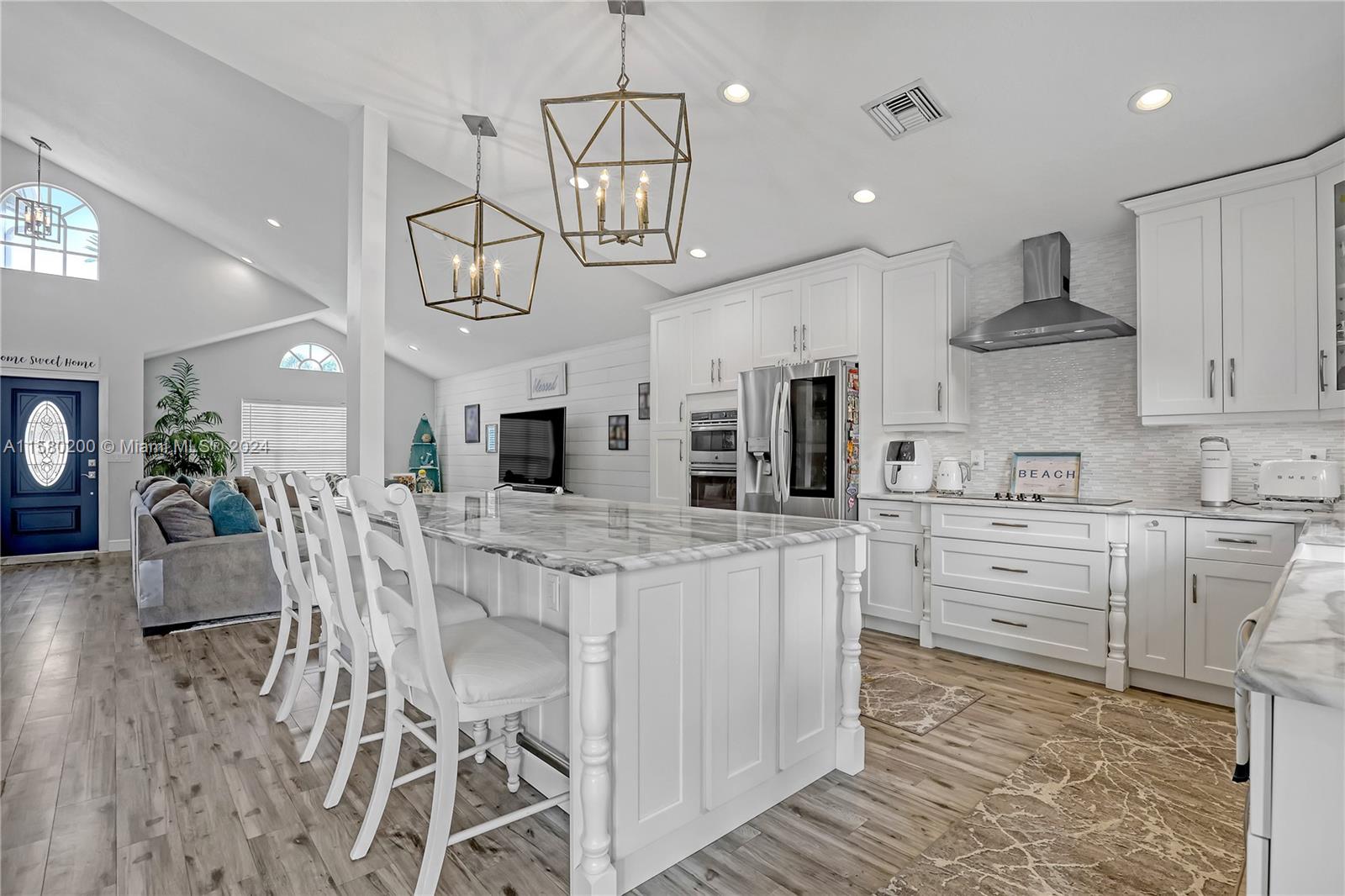 147 Stonebriar Boulevard Jupiter, FL 33458 - Photo 14 of 39 a kitchen with stainless steel appliances kitchen island granite countertop a table and chairs in it