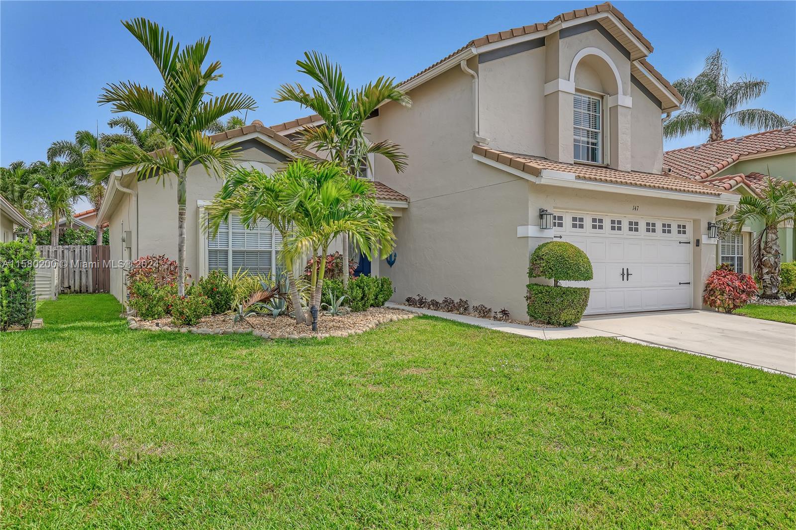 147 Stonebriar Boulevard Jupiter, FL 33458 - Photo 3 of 39 a front view of a house with a garden and yard