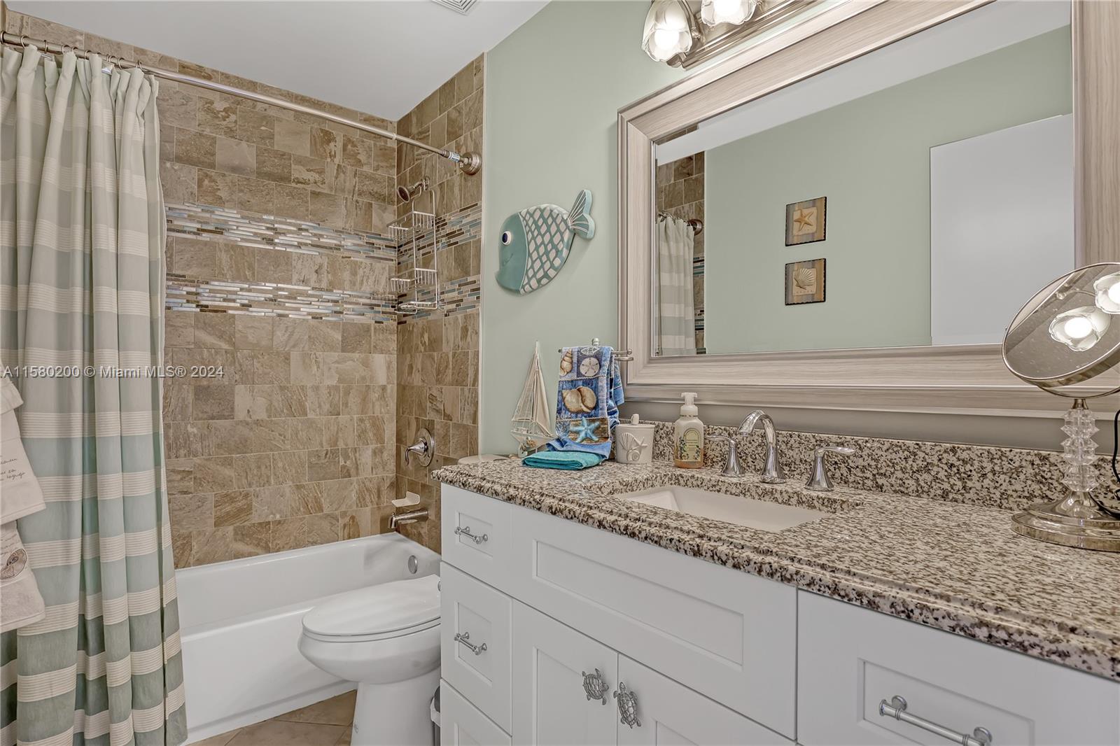 147 Stonebriar Boulevard Jupiter, FL 33458 - Photo 31 of 39 a bathroom with a granite countertop sink a toilet a mirror a bathtub and shower