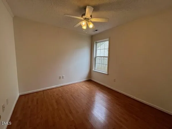 an empty room with a window and a ceiling fan