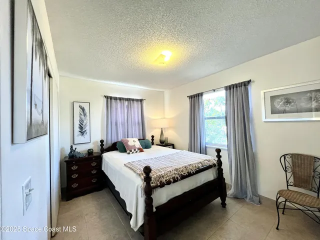 a bedroom with a bed table chair and a window