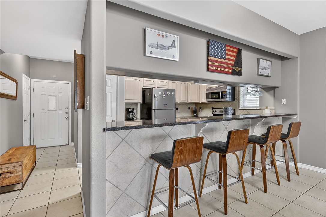 14427 Compass Street, Unit A6 Corpus Christi, TX 78418 - Photo 6 of 40 a kitchen with stainless steel appliances kitchen island granite countertop a refrigerator and a stove top oven