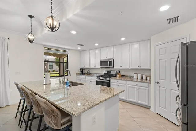 a kitchen with stainless steel appliances granite countertop a sink a stove a refrigerator cabinets and chairs