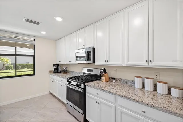 a kitchen with granite countertop white cabinets and stainless steel appliances