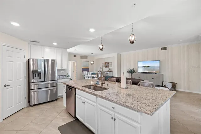 a kitchen with stainless steel appliances granite countertop a sink refrigerator and cabinets