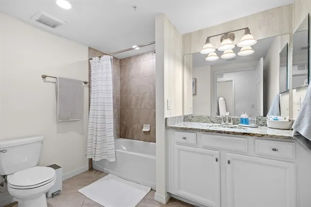 a bathroom with a granite countertop sink a toilet a mirror a vanity and shower