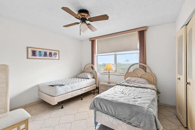 a bedroom with two beds and ceiling fan