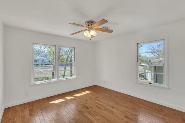 a view of empty room with wooden floor and fan