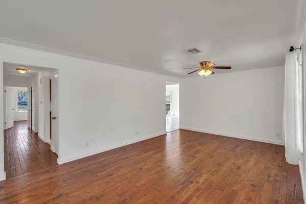 a view of empty room with wooden floor and fan