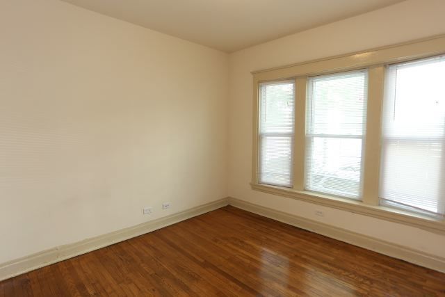 4716 North Racine Avenue, Unit 2E Chicago, IL 60640 - Photo 7 of 19 an empty room with wooden floor and windows
