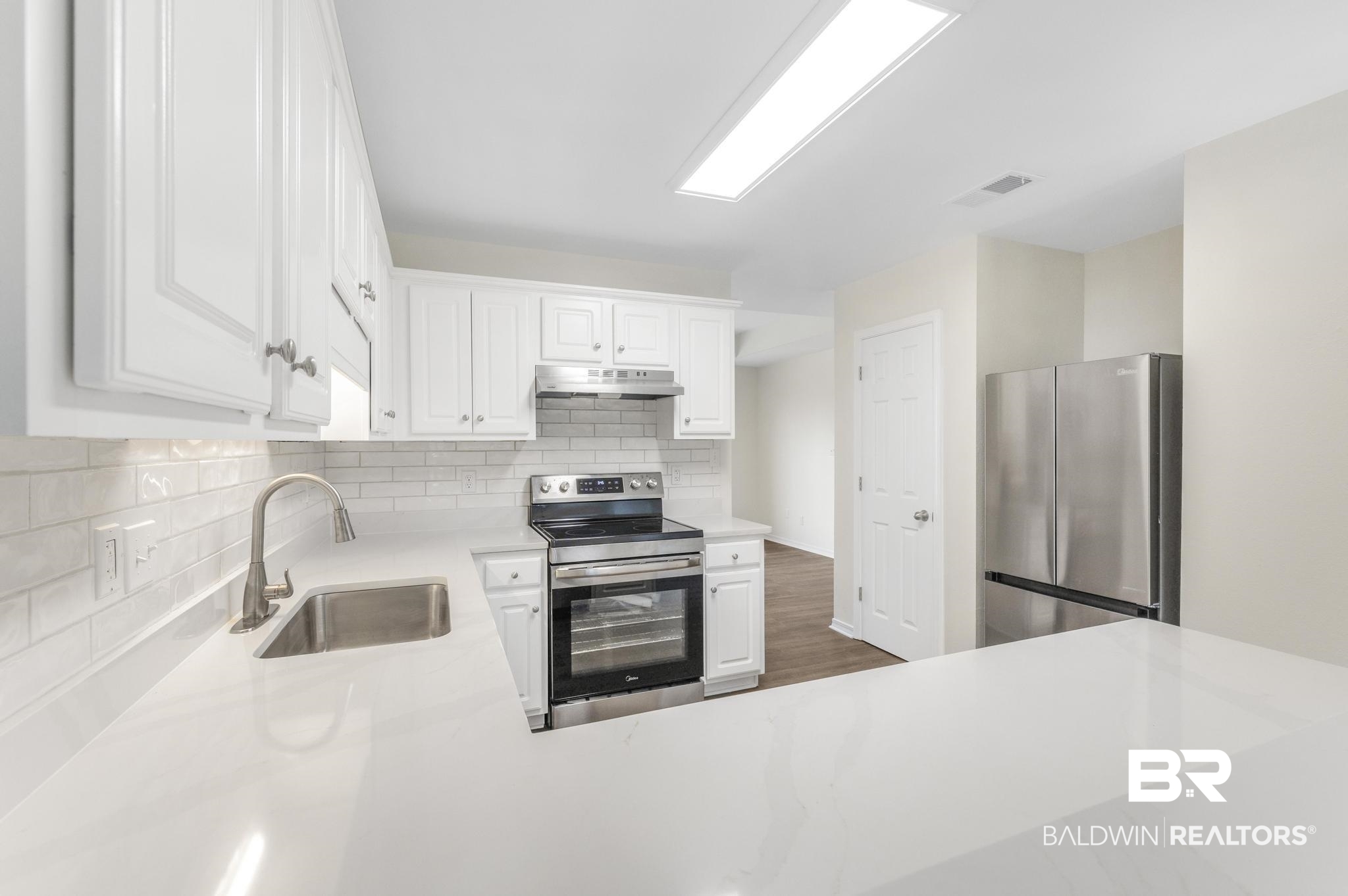 16330 Absalom Street Foley, AL 36535 - Photo 21 of 42 Kitchen featuring appliances with stainless steel finishes, dark hardwood / wood-style floors, tasteful backsplash, sink, and white cabinets