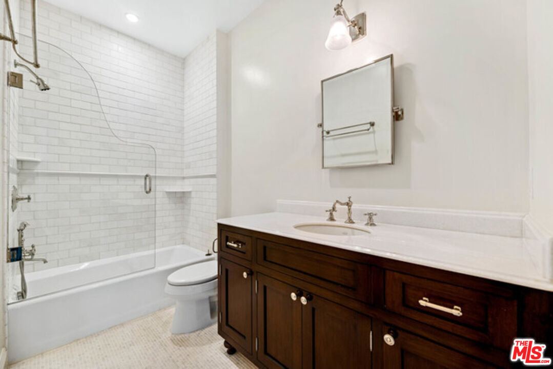 9233 1/2 Doheny Road West Hollywood, CA 90069 - Photo 13 of 17 a bathroom with a granite countertop sink a toilet a mirror and bathtub