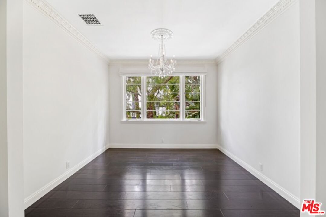 9233 1/2 Doheny Road West Hollywood, CA 90069 - Photo 8 of 17 an empty room with wooden floor chandelier and windows