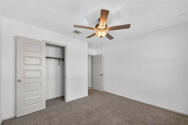 an empty room with closet and ceiling fan