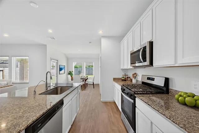 a kitchen with granite countertop a sink a counter top space stainless steel appliances and cabinets