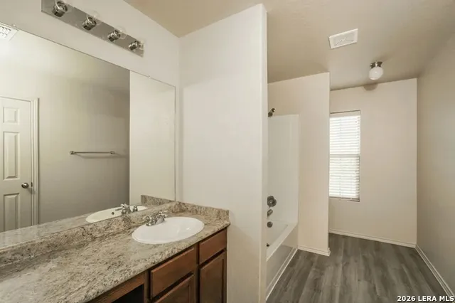 a bathroom with a granite countertop sink a mirror and a shower