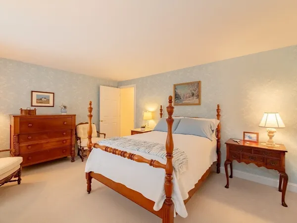 a spacious bedroom with a bed and a lamp on table