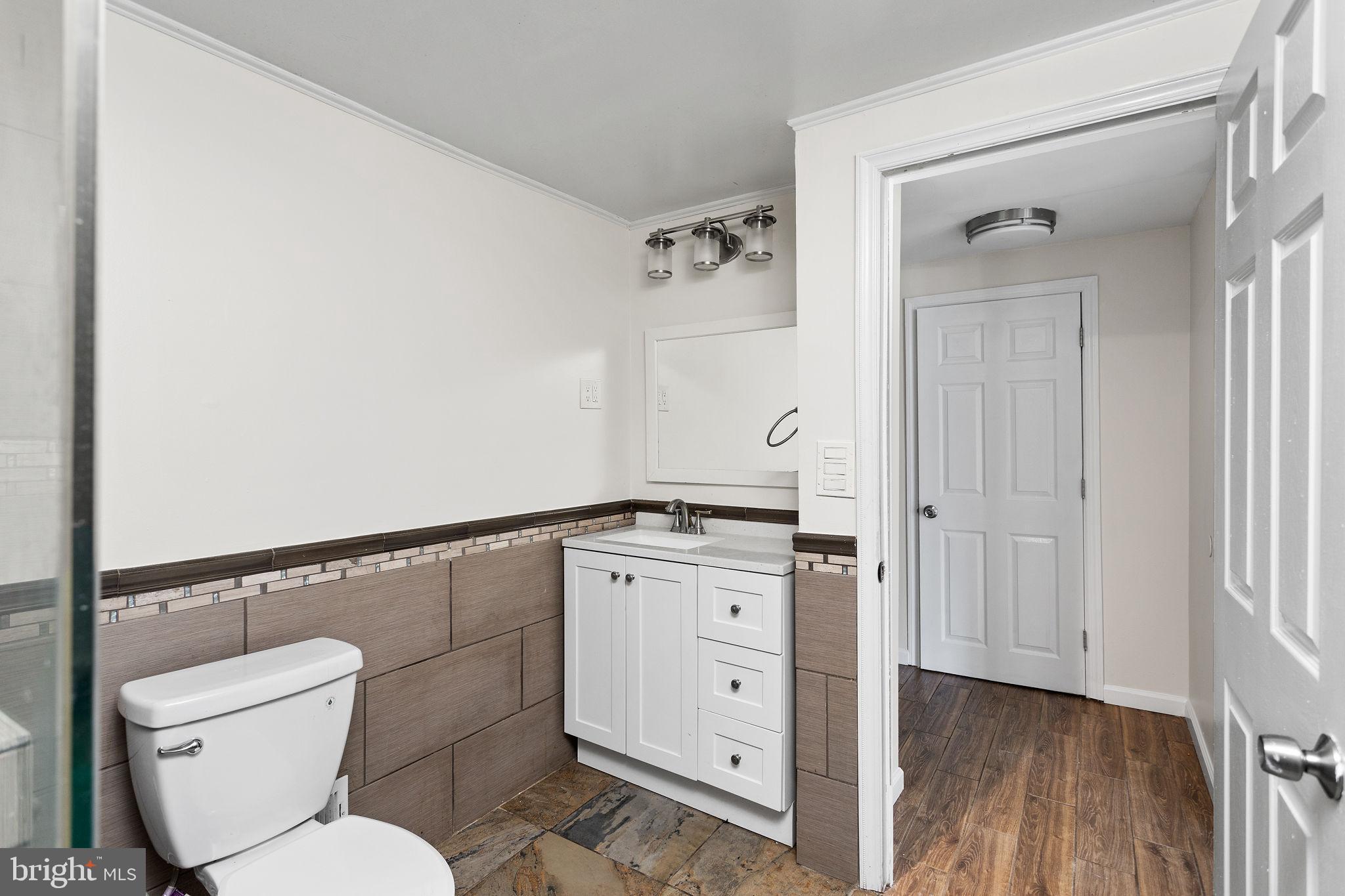 2264 Pennington Road Trenton, NJ 08638 - Photo 13 of 24 a bathroom with a toilet a sink and wooden floor