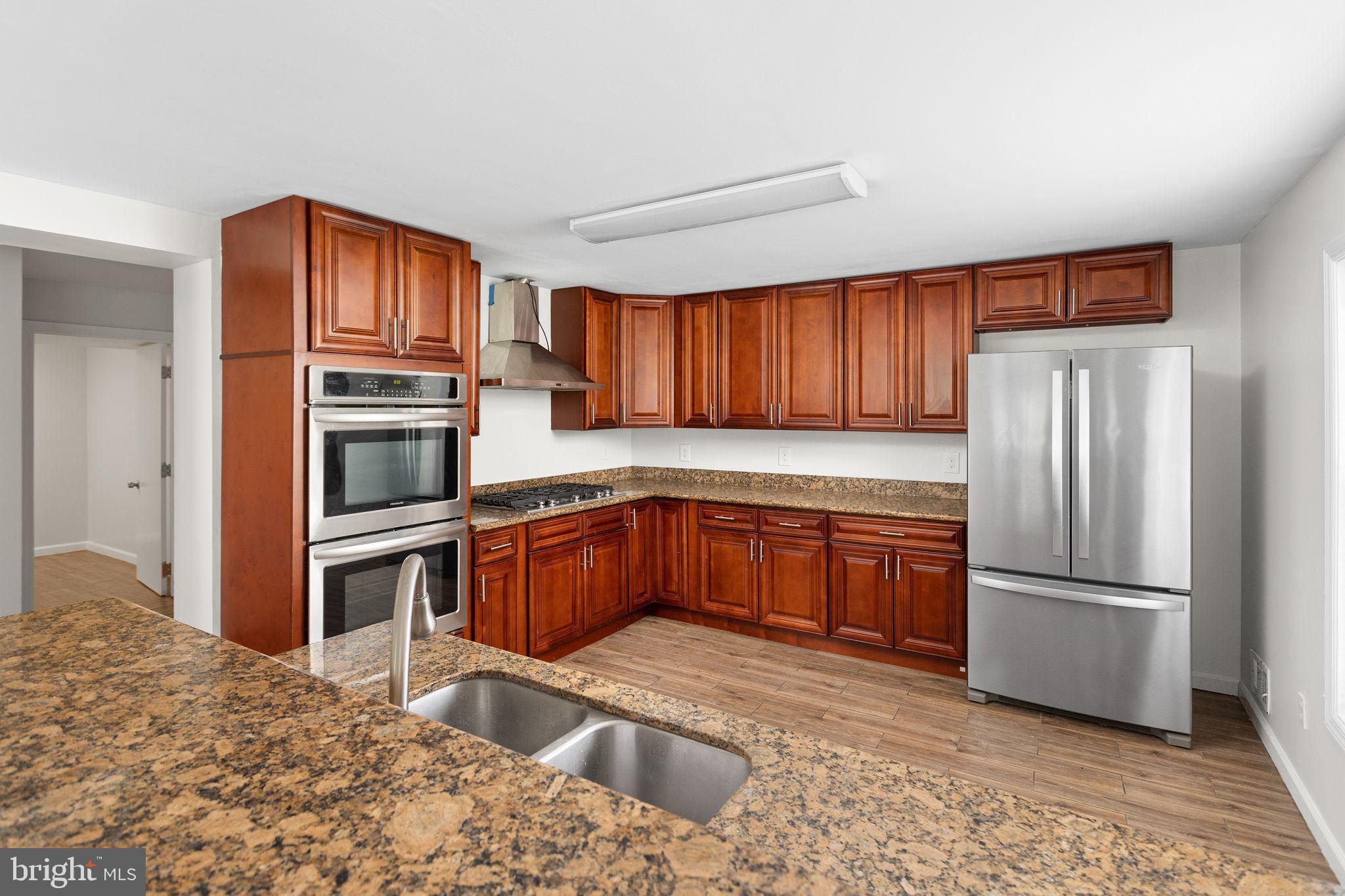 2264 Pennington Road Trenton, NJ 08638 - Photo 10 of 24 a kitchen with granite countertop wooden cabinets a stove top oven and stainless steel appliances