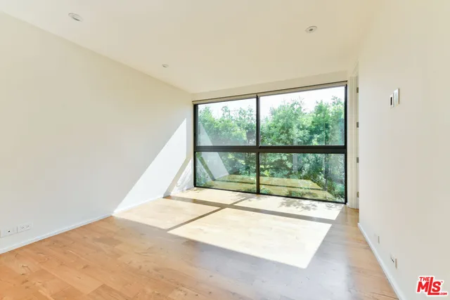 a view of a big room with wooden floor and windows
