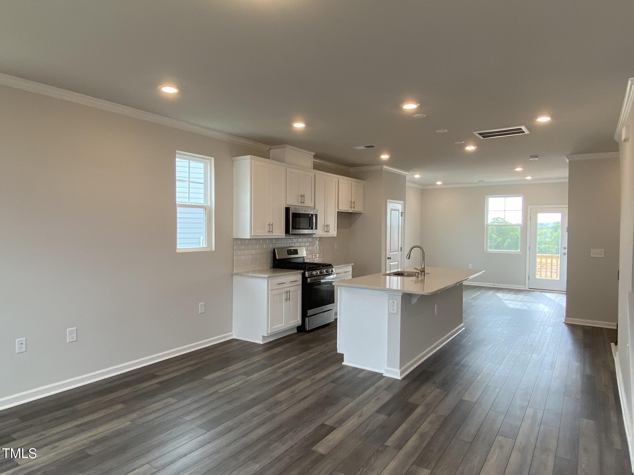 722 Gimari Drive Wake Forest, NC 27587 - Photo 10 of 25 a kitchen with a sink wooden floor stainless steel appliances and cabinets