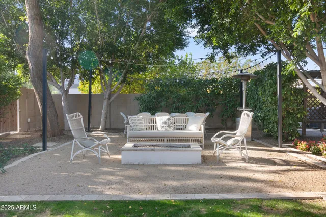 a white bench sitting in a yard with large trees