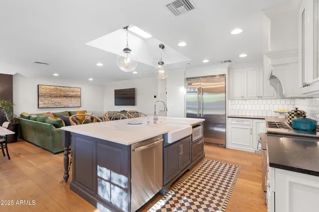 a large kitchen with kitchen island a sink a counter top space and stainless steel appliances