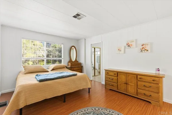 a bedroom with a bed and a dresser next to a window