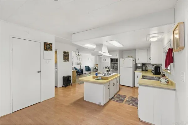 a living room with stainless steel appliances kitchen island a table chairs in it and a window