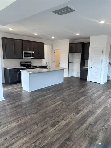 a view of kitchen with kitchen island granite countertop a stove top oven a sink and dishwasher a refrigerator with wooden floor