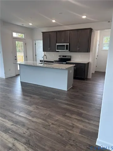 a kitchen with stainless steel appliances kitchen island granite countertop a stove a sink and white cabinets