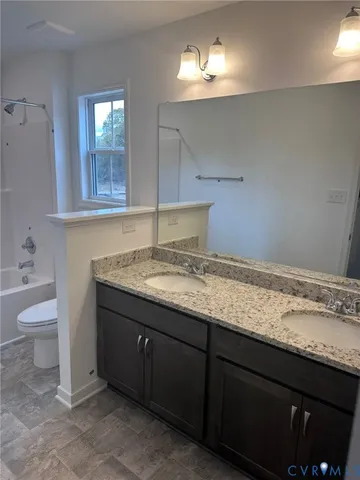 a bathroom with a granite countertop sink and a toilet