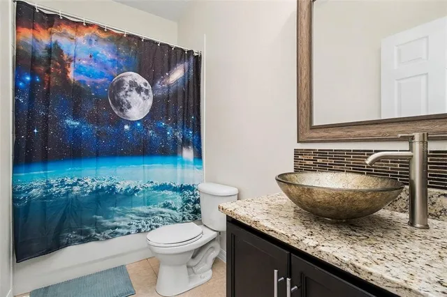 a bathroom with a granite countertop toilet and a sink