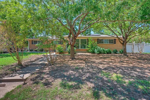 a front view of a house with a yard and trees