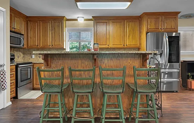 a kitchen with stainless steel appliances granite countertop a stove top oven a refrigerator and cabinets