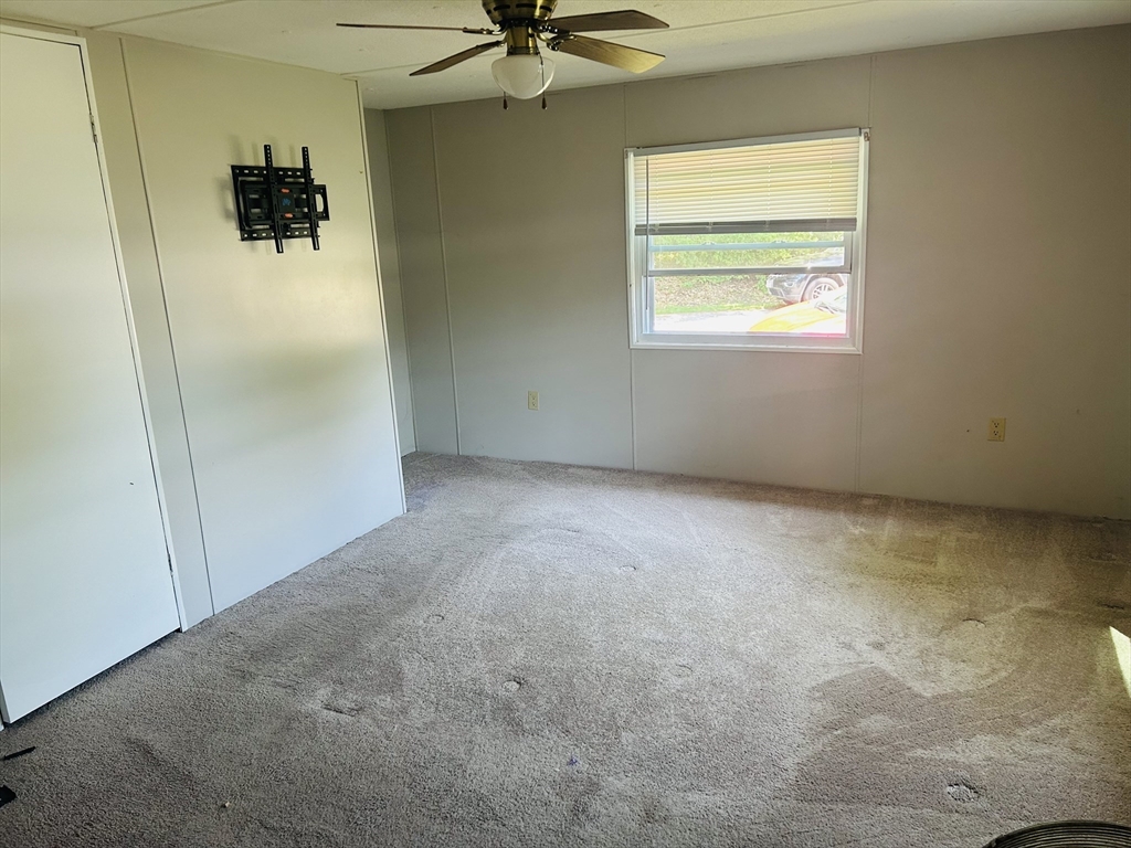 735 Memorial Drive, Unit 115 Chicopee, MA 01020 - Photo 5 of 8 an empty room with a window and a ceiling fan