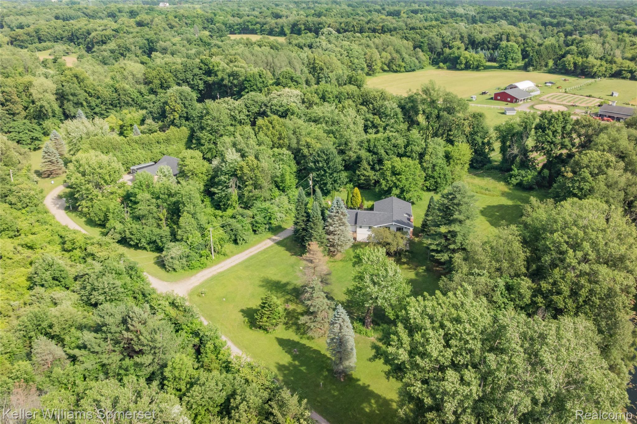 2344 Rochester Road Leonard, MI 48367 - Photo 64 of 66 Expansive wooded acreage featuring a main residence with a dark shingle roof, mature trees, and a winding driveway