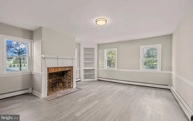 an empty room with windows and fireplace