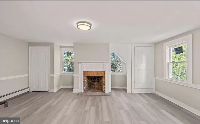 an empty room with windows and fireplace