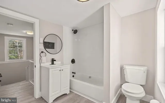 a bathroom with a toilet a sink a mirror and tub