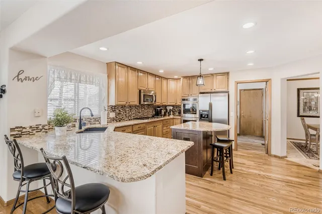 a kitchen with stainless steel appliances granite countertop a table chairs stove and refrigerator