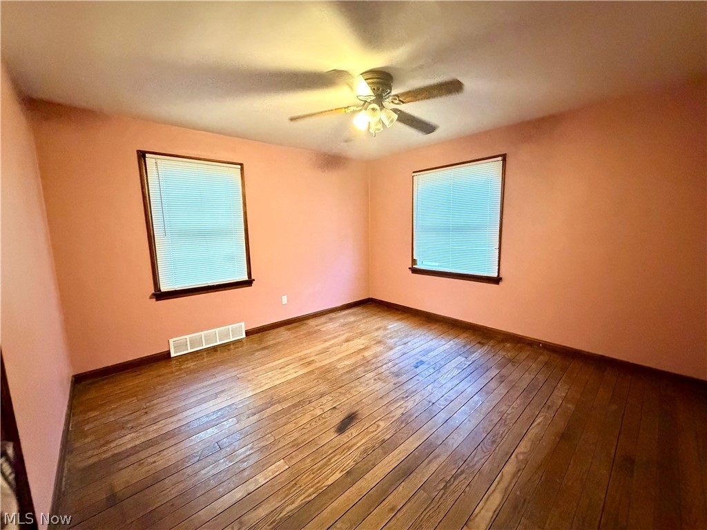 10506 Park Heights Road Cleveland, OH 44104 - Photo 10 of 22 Room featuring wood-finish flooring, two windows with blinds, a ceiling fan with integrated lighting, and painted walls