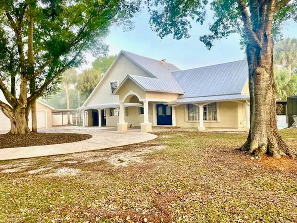 a view of a yard in front of a house with a large tree